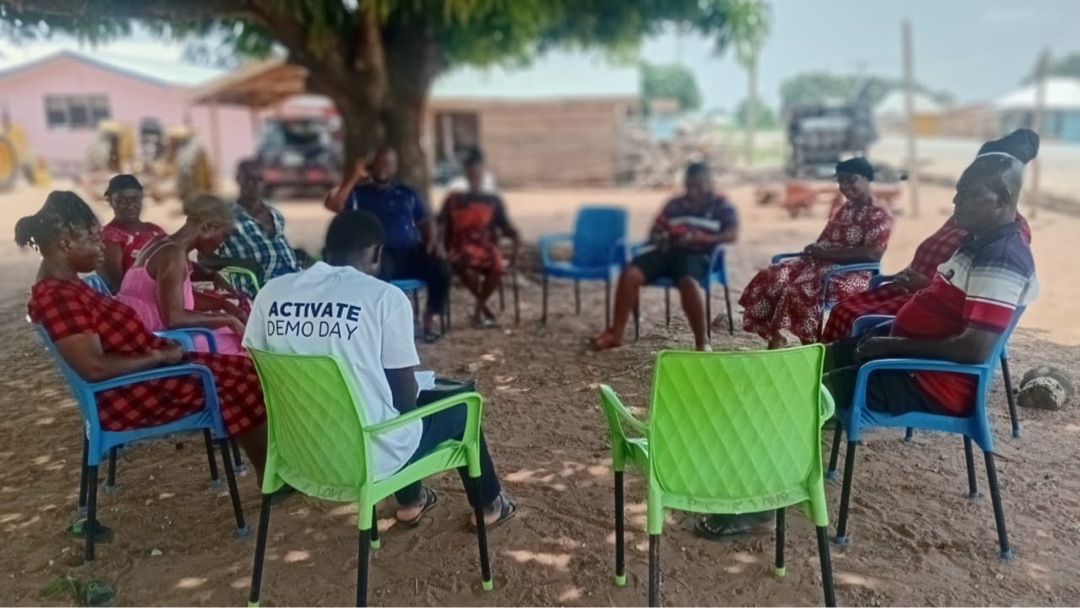 Community engagement session with farmers under a shade tree